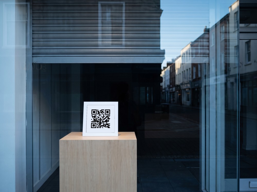 A single card on an empty plinth in a dark shop window, early in the morning